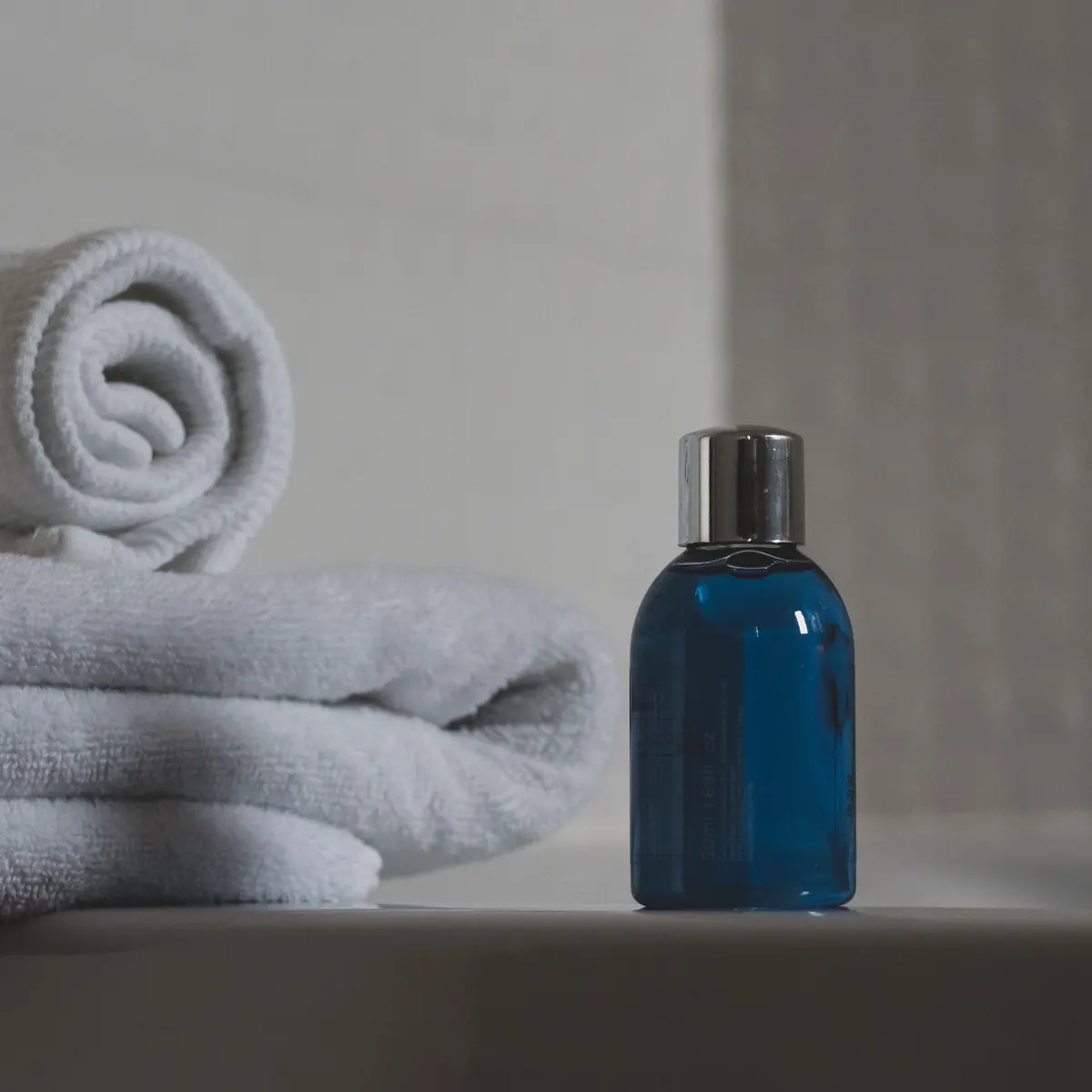 Toalha branca ao lado de um frasco azul